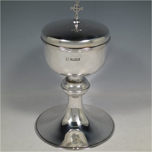 A Scottish Sterling Silver Ciborium, having a plain round body, sitting on a matching pedestal foot with applied reeded borders, and a lift-off lid with cruciform finial. Made by H. D. Falconer & Son of Glasgow in 1945. The dimensions of this fine hand-made silver ciborium are height 22 cms (8.75 inches), diameter of cup 11 cms (4.25 inches), and it weighs a total of approx. 530g (17 troy ounces).   