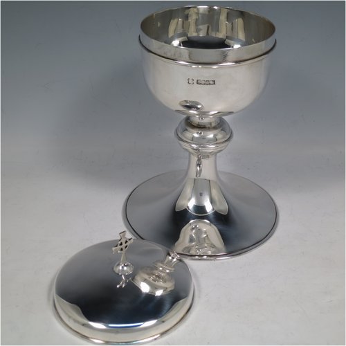 A Scottish Sterling Silver Ciborium, having a plain round body, sitting on a matching pedestal foot with applied reeded borders, and a lift-off lid with cruciform finial. Made by H. D. Falconer & Son of Glasgow in 1945. The dimensions of this fine hand-made silver ciborium are height 22 cms (8.75 inches), diameter of cup 11 cms (4.25 inches), and it weighs a total of approx. 530g (17 troy ounces).   