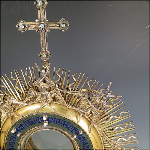 An Antique Victorian Sterling Silver and gold-gilt Monstrance, having a cruciform finial over a central Lunar receptacle in an elaborate sun-ray frame with eight applied winged angels, all mounted on a pedestal foot with hand-chased vine-leaf central knop over a hexafoil base. All decorated with 39 old cut foil-backed diamonds (one missing), 15 pearls of good lustre and uneven shape, a blue-enamelled Lunar surround engraved with the Latin Sanctus repeated, and 27 set turquoise stones. Made by John Harman & Co., of Birmingham in 1899. The dimensions of this fine hand-made antique silver and gold-gilt Monstrance are height 68 cms (26.75 inches), width 29 cms (11.5 inches), depth 25.5 cms (10 inches), and it weighs approx. 2,800g (90 troy ounces). Please note that the overall total estimated diamond weight is 5.5 carats).  