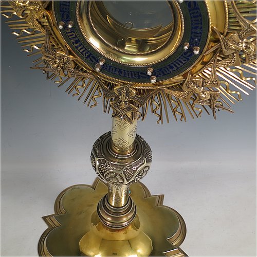 An Antique Victorian Sterling Silver and gold-gilt Monstrance, having a cruciform finial over a central Lunar receptacle in an elaborate sun-ray frame with eight applied winged angels, all mounted on a pedestal foot with hand-chased vine-leaf central knop over a hexafoil base. All decorated with 39 old cut foil-backed diamonds (one missing), 15 pearls of good lustre and uneven shape, a blue-enamelled Lunar surround engraved with the Latin Sanctus repeated, and 27 set turquoise stones. Made by John Harman & Co., of Birmingham in 1899. The dimensions of this fine hand-made antique silver and gold-gilt Monstrance are height 68 cms (26.75 inches), width 29 cms (11.5 inches), depth 25.5 cms (10 inches), and it weighs approx. 2,800g (90 troy ounces). Please note that the overall total estimated diamond weight is 5.5 carats).  