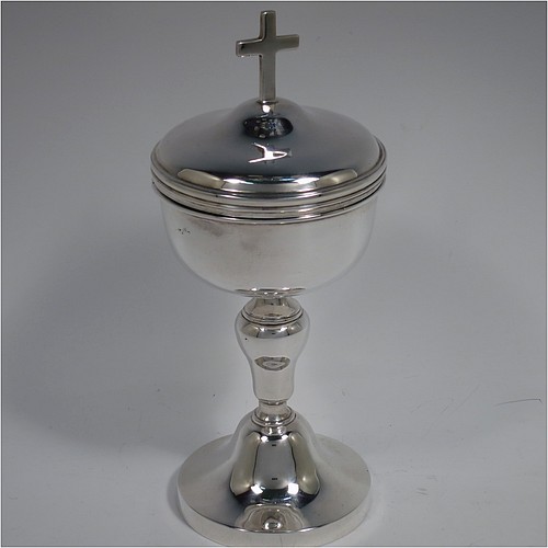 An Antique Edwardian Sterling Silver Ciborium, having a plain round body with reeded borders and gold-gilt interior, sitting on a matching pedestal foot with central baluster, and a lift-off lid with cruciform finial. Made by Henry Lambert of London in 1902. The dimensions of this fine hand-made antique silver ciborium are height 19 cms (7.5 inches), diameter of cup 8.5 cms (3.3 inches), and it weighs a total of approx. 264g (8.5 troy ounces).    