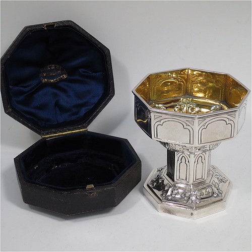 An Antique Victorian Sterling Silver very rare and unusual travelling chalice, in the shape of an octagonal shaped baptismal font, the top piece, which screws into the base, having a gold-gilt interior and hand-chased panels with anthemion leaves and angel faces, the pedestal base with matching panel work and leaves, and all in its original dark-blue satin and velvet-lined presentation box. Made by George Fox of London in 1863. The dimensions of this fine hand-made antique silver travelling chalice are height 10 cms (4 inches), diameter at top 9 cms (3.5 inches), with a total weight of approx. 172g (5.5 troy ounces).    