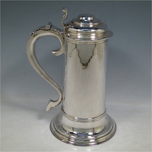 A Sterling Silver communion flagon for wine, in an early 17th century style having a straight-sided body, a scroll handle, a hinged & domed lid with cast scroll thumb-piece, and sitting on a collet foot. Made by J. Wippell & Co., of London in 1931. The dimensions of this fine hand-made communion wine flagon are height 25 cms (9.75 inches), length across handle & spout 18 cms (7 inches),and it weighs approx. 985g (32 troy ounces).   