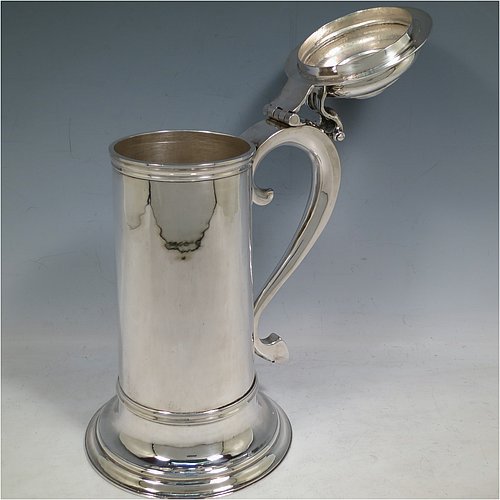 A Sterling Silver communion flagon for wine, in an early 17th century style having a straight-sided body, a scroll handle, a hinged & domed lid with cast scroll thumb-piece, and sitting on a collet foot. Made by J. Wippell & Co., of London in 1931. The dimensions of this fine hand-made communion wine flagon are height 25 cms (9.75 inches), length across handle & spout 18 cms (7 inches),and it weighs approx. 985g (32 troy ounces).   