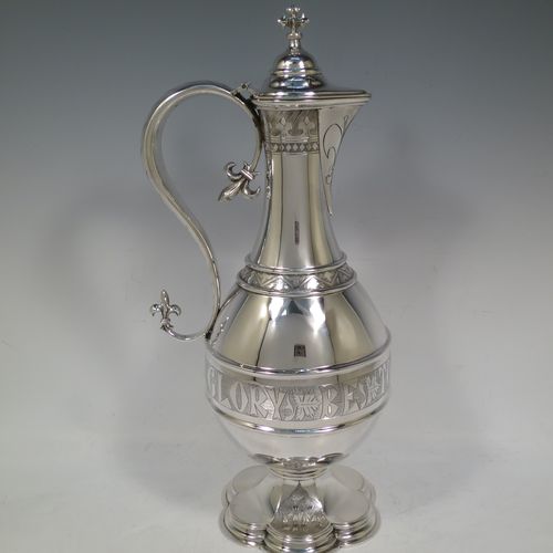 A very beautiful and large Antique Victorian Sterling Silver ecclesiastical wine or water ewer, having a round bellied body with applied bands and a central girdle with a hand-engraved Glory Be To God On High, together with a hinged domed lid with a a cast double cross finial, a sparrow-beak spout with an engraved fleur-de-lis, a scroll handle with cast fleur-de-lis terminals, and sitting on a spreading hexafoil foot with engraved christograms. Made by John Keith of London in 1862. The dimensions of this fine hand-made antique silver flagon or ewer are height 35 cms (13.75 inches), length 15 cms (6 inches), and it weighs approx. 815g (26 troy ounces).    