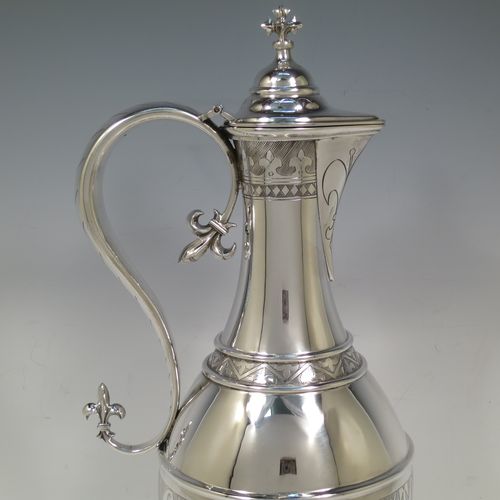 A very beautiful and large Antique Victorian Sterling Silver ecclesiastical wine or water ewer, having a round bellied body with applied bands and a central girdle with a hand-engraved Glory Be To God On High, together with a hinged domed lid with a a cast double cross finial, a sparrow-beak spout with an engraved fleur-de-lis, a scroll handle with cast fleur-de-lis terminals, and sitting on a spreading hexafoil foot with engraved christograms. Made by John Keith of London in 1862. The dimensions of this fine hand-made antique silver flagon or ewer are height 35 cms (13.75 inches), length 15 cms (6 inches), and it weighs approx. 815g (26 troy ounces).    