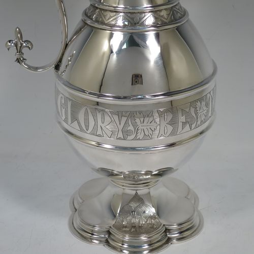 A very beautiful and large Antique Victorian Sterling Silver ecclesiastical wine or water ewer, having a round bellied body with applied bands and a central girdle with a hand-engraved Glory Be To God On High, together with a hinged domed lid with a a cast double cross finial, a sparrow-beak spout with an engraved fleur-de-lis, a scroll handle with cast fleur-de-lis terminals, and sitting on a spreading hexafoil foot with engraved christograms. Made by John Keith of London in 1862. The dimensions of this fine hand-made antique silver flagon or ewer are height 35 cms (13.75 inches), length 15 cms (6 inches), and it weighs approx. 815g (26 troy ounces).    