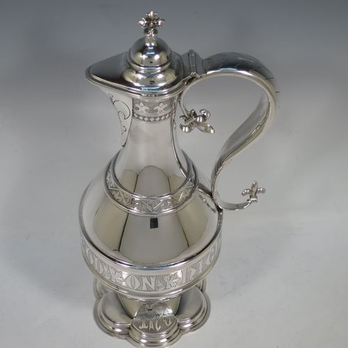 A very beautiful and large Antique Victorian Sterling Silver ecclesiastical wine or water ewer, having a round bellied body with applied bands and a central girdle with a hand-engraved Glory Be To God On High, together with a hinged domed lid with a a cast double cross finial, a sparrow-beak spout with an engraved fleur-de-lis, a scroll handle with cast fleur-de-lis terminals, and sitting on a spreading hexafoil foot with engraved christograms. Made by John Keith of London in 1862. The dimensions of this fine hand-made antique silver flagon or ewer are height 35 cms (13.75 inches), length 15 cms (6 inches), and it weighs approx. 815g (26 troy ounces).    