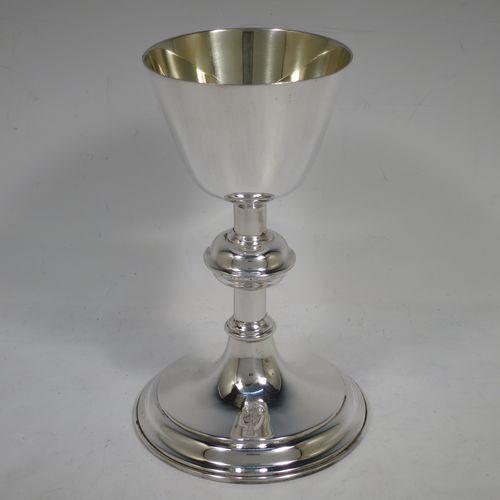 A handsome antique Sterling Silver altar chalice, having a plain round tapering cup with a gold-gilt interior, a middle plain round baluster, sitting on a round stepped pedestal foot. Made by Jesse Earls of London in 1919. The dimensions of this fine hand-made antique silver chalice are height 18 cms (7 inches), diameter at base 11.5 cms (4.5 inches), and  it weighs approx. 204g (6.6 troy ounces).    