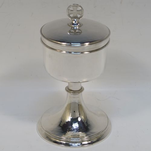 A small but handsome Sterling Silver Ciborium, having a round body with hand-hammered or planished decoration and reeded borders, a plain round lift-off lid with a cruciform finial, and all sitting on a round pedestal foot base. This elegant silver ciborium was made by John Wippell and Co. Ltd., of London in 1943. The dimensions of this fine hand-made silver ciborium are height 14.5 cms (5.75 inches), diameter of cup 7.5 cms (3 inches), and it weighs a total of approx. 237g (7.6 troy ounces).