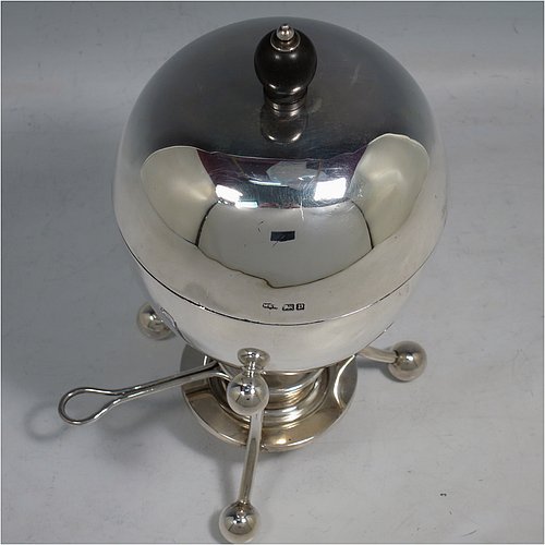 A rare Antique Edwardian Sterling Silver egg coddler, having a plain round body, with lift-off lid and wooden finial, sitting in a wire-work frame with ball terminals, an interior egg-holder for four eggs, and an original burner, all sitting on four ball feet. Made by Mappin & Webb of Sheffield in 1907. The dimensions of this fine hand-made antique silver egg coddler are height 23 cms (9 inches), diameter 11 cms (4.3 inches), and it weighs approx. 510g (16.5 troy ounces).   