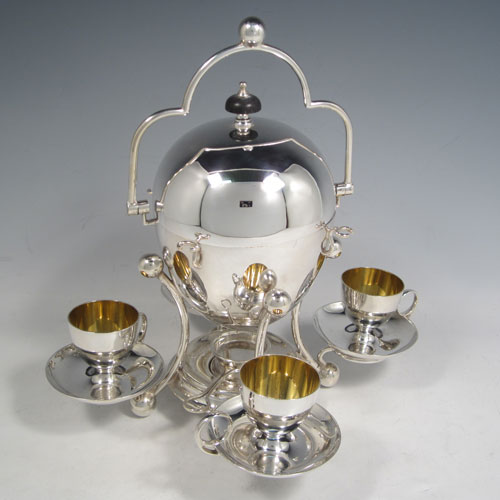 Antique Edwardian silver-plated egg coddler, having a plain round body with lift-off lid, sitting in a frame with swing handle, with four removable egg cups, an interior egg-holder, and an original burner, all sitting on four ball feet. Made in ca. 1900. The dimensions of this fine hand-made silver plated egg coddler are height 27 cms (10.5 inches), and width 26 cms (10.25 inches).