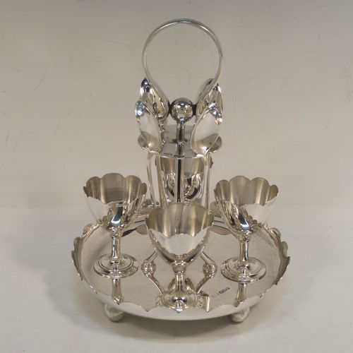 A pretty Sterling Silver egg cruet set, having a plain round body with a scalloped border, four plain round egg cups, a loop handle and holder with four original egg spoons, and all sitting on four ball feet. This elegant silver egg cruet set was all made by John Batt of Sheffield in 1924. The dimensions of this fine hand-made silver egg cruet set are height 18.5 cms (7.25 inches), diameter of main body 14.5 cms (5.75 inches), with a total weight of approx. 543g (17.5 troy ounces).   