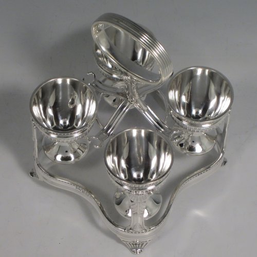 Sterling silver egg cruet set, having four round egg cups, sitting inside a frame with gadroon, shell, and anthemion leaf decoration, and a reeded loop handle, all sitting on four flange feet. Made by George Hancock of Sheffield in 1915. Please note that there are no spoons with this stand. The dimensions of this fine hand-made silver egg cruet set are height 16 cms (6.25 inches), the base is 11 cms (4.3 inches) square and the total weight is approx. 483g (15.6 troy ounces).   