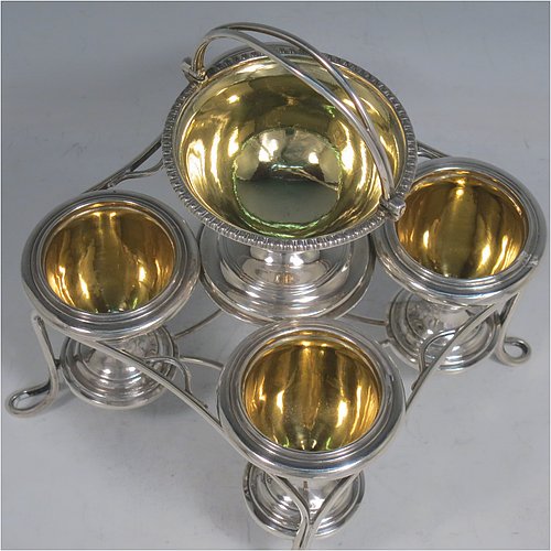 An Antique Georgian Sterling Silver egg cruet set, having four removable plain round egg cups, an unusual central condiment bowl for either salt or pepper with swing-handle, all with gold-gilt interiors, and all sitting in a wire-work frame stand with four feet. Made by Waterhouse, Hodson & Co., of Sheffield in 1828. The dimensions of this fine hand-made antique silver egg cruet set are height 18 cms (7 inches), width 17 cms (6.75 inches), with a total weight of approx. 530g (17 troy ounces).    