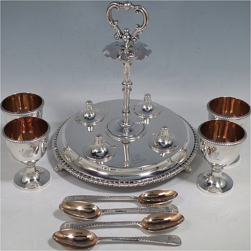 A very pretty Antique Victorian Sterling Silver egg cruet set, having a round body with applied gadroon borders, four plain round egg cups sitting on pedestal feet, and a cast loop handle attached to a round base sitting on four flange feet. Made by Andrew Crespel and Thomas Parker of London in 1867. The matching spoons are made by Jackson & Fullerton of London in 1906. The spoon and egg cup bowl interiors are all gold-gilt. The dimensions of this fine hand-made antique silver egg cruet set are height 18 cms (7 inches), diameter of base 17 cms (6.75 inches), and the total weight is approx. 856g (27.6 troy ounces). Please note that all items in this set are crested.