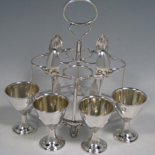    Antique Victorian sterling silver egg cruet set, having four removable plain round egg cups with gold-gilt interiors, a wire-work frame stand sitting on four cast foliate feet, and four egg spoons in the Fiddle pattern. All pieces are part-crested with a leopards head. The stand and egg cups are all made by Joseph Angel of London in 1856, whilst the four spoons are made by John Stone of Exeter in 1854. Height 19 cms (7.5 inches), length 15 cms (6 inches). Total weight approx. 485g (15.6 troy ounces).