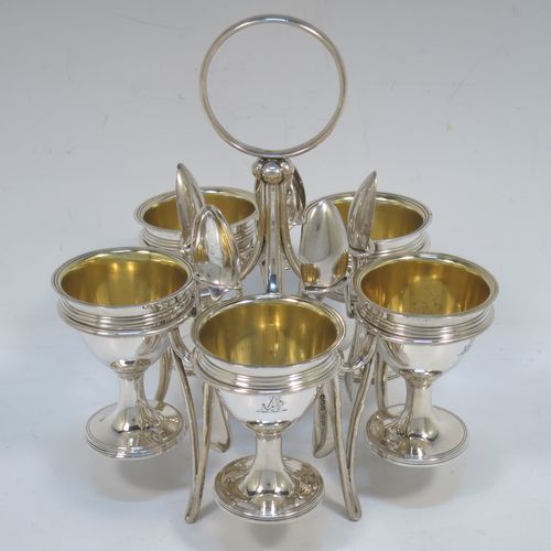 A very handsome Antique Victorian Sterling Silver egg cruet set, having five removable plain round egg cups with reeded borders and gold-gilt interiors, all sitting in a plain wire-work frame stand with five feet, together with five matching plain Old English pattern spoons. The cruet frame and egg cups made by the Barnard Brothers of London in 1859, and the spoons made by James Dixon and Sons of Sheffield in 1922. The dimensions of this fine hand-made antique silver egg cruet set are height 18 cms (7 inches), width 15 cms (6 inches), with a total weight of approx. 477g (15.4 troy ounces).  