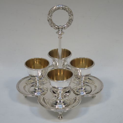 A very pretty Antique Victorian Sterling Silver egg cruet set, having four plain round egg cups with bead borders and gold-gild interiors sitting on pedestal feet, together with a cast laurel leaf loop handle attached to a lobed base with an applied bead-edged border, and all sitting on four cast claw and ball feet. Made by Elkington and Co., of Birmingham in 1866. The dimensions of this fine hand-made antique silver egg cruet set are height 18 cms (7 inches), width of base is 16.5 cms (6.5 inches), and the total weight is approx. 500g (16 troy ounces).  