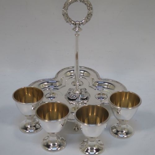 A very pretty Antique Victorian Sterling Silver egg cruet set, having four plain round egg cups with bead borders and gold-gild interiors sitting on pedestal feet, together with a cast laurel leaf loop handle attached to a lobed base with an applied bead-edged border, and all sitting on four cast claw and ball feet. Made by Elkington and Co., of Birmingham in 1866. The dimensions of this fine hand-made antique silver egg cruet set are height 18 cms (7 inches), width of base is 16.5 cms (6.5 inches), and the total weight is approx. 500g (16 troy ounces).  