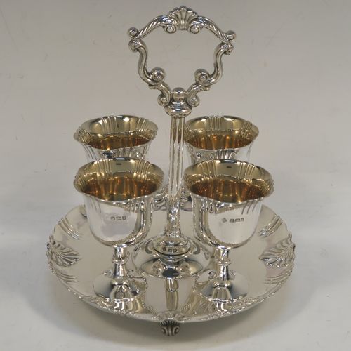 A very pretty Antique Victorian Sterling Silver egg cruet set with hand-chased fluted and shell decoration, having egg cups with gold-gilt interiors, and a cast shell and scroll loop handle attached to a round base sitting on four cast scrolled feet. This beautiful antique silver egg cruet set was made by Martin Hall and Co., of Sheffield in 1892 / 1898 (two of the egg cups are from 1892). The dimensions of this fine hand-made silver egg cruet set are height 18 cms (7 inches), the base is 15 cms (6 inches) in diameter, and the total weight is approx. 505g (16.3 troy ounces).  