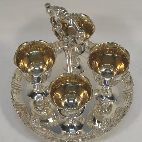 A very pretty Antique Victorian Sterling Silver egg cruet set with hand-chased fluted and shell decoration, having egg cups with gold-gilt interiors, and a cast shell and scroll loop handle attached to a round base sitting on four cast scrolled feet. This beautiful antique silver egg cruet set was made by Martin Hall and Co., of Sheffield in 1892 / 1898 (two of the egg cups are from 1892). The dimensions of this fine hand-made silver egg cruet set are height 18 cms (7 inches), the base is 15 cms (6 inches) in diameter, and the total weight is approx. 505g (16.3 troy ounces).  