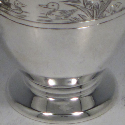 Sterling silver egg cup, having a plain round body with tapering sides, with a hand-engraved top border (showing ducks, ducklings, reeds, chickens, and chicks), with two scroll side-handles, and sitting on a pedestal foot. Made by R.W. Brookes for Harrods, London, in 1925. The dimensions of this fine hand-made silver egg cup are height 4.5 cms (1.75 inches), width 7 cms (2.75 inches), and it weighs approx. 44g (1.4 troy ounces).