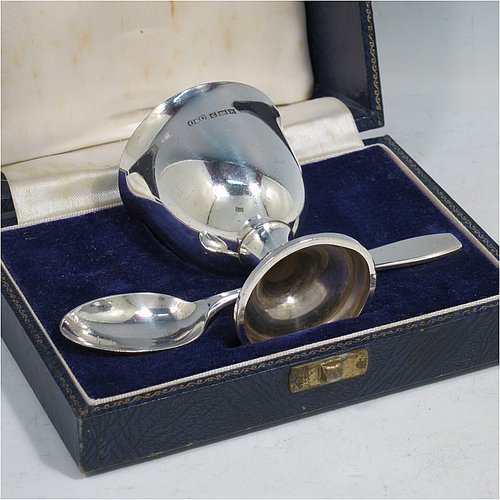 A Sterling Silver christening set, having a plain round egg cup, and a plain pattern spoon. All fitted in their original cream satin and blue velvet-lined presentation box. Made in Birmingham in 1964. The dimensions of this fine hand-made silver christening set are length of spoon 11 cms (4.3 inches), height of egg cup 6.5 cms (2.5 inches), and the total weight is approx. 50g (1.6 troy ounce).    