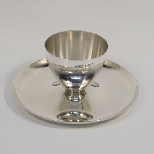 A Sterling Silver egg cup and plate, having a plain round body with tapering sides, with an attached plain round plate with curved border, and sitting on a flat base. This elegant silver egg cup was made by James Dixon Sons of Sheffield in 1943. The dimensions of this fine hand-made silver egg cup are height 4 cms (1.5 inches), diameter 9.5 cms (3.75 inches), and it weighs approx. 77g (2.5 troy ounces).  