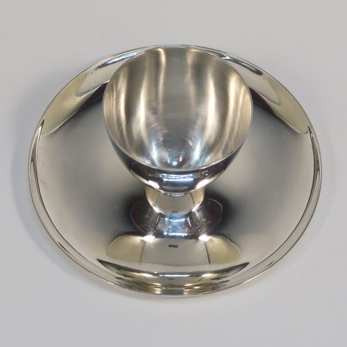 A Sterling Silver egg cup and plate, having a plain round body with tapering sides, with an attached plain round plate with curved border, and sitting on a flat base. This elegant silver egg cup was made by James Dixon Sons of Sheffield in 1943. The dimensions of this fine hand-made silver egg cup are height 4 cms (1.5 inches), diameter 9.5 cms (3.75 inches), and it weighs approx. 77g (2.5 troy ounces).  