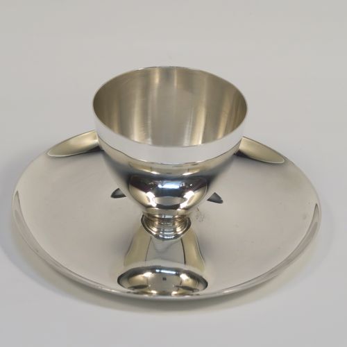 A Sterling Silver egg cup and plate, having a plain round body with tapering sides, with an attached plain round plate with curved border, and sitting on a flat base. This elegant silver egg cup was made by James Dixon Sons of Sheffield in 1943. The dimensions of this fine hand-made silver egg cup are height 4 cms (1.5 inches), diameter 9.5 cms (3.75 inches), and it weighs approx. 77g (2.5 troy ounces).  