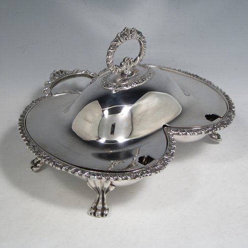 Antique Victorian silver plated double entree dish, having a very unusual double oval dish style, with removable cover and handle, applied gadroon and shell borders, a further side handle, and sitting on four cast lions-paw feet. Made in ca. 1890. The dimensions of this fine double entree dish and cover are height 15 cms (6 inches), length 23 cms (9 inches), and width 21.5 cms (8.5 inches).