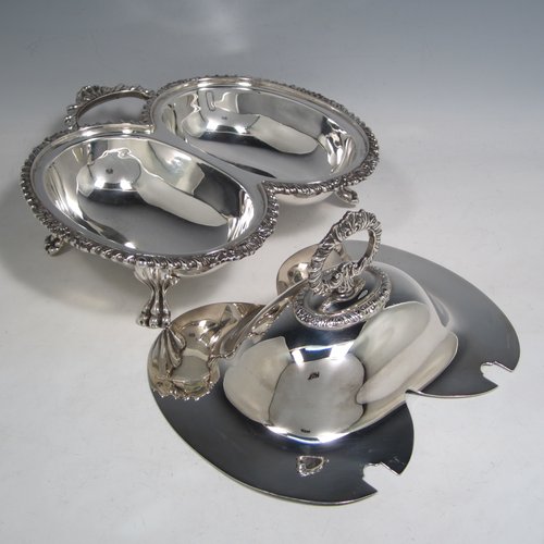 Antique Victorian silver plated double entree dish, having a very unusual double oval dish style, with removable cover and handle, applied gadroon and shell borders, a further side handle, and sitting on four cast lions-paw feet. Made in ca. 1890. The dimensions of this fine double entree dish and cover are height 15 cms (6 inches), length 23 cms (9 inches), and width 21.5 cms (8.5 inches).