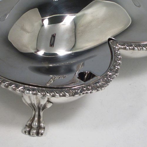 Antique Victorian silver plated double entree dish, having a very unusual double oval dish style, with removable cover and handle, applied gadroon and shell borders, a further side handle, and sitting on four cast lions-paw feet. Made in ca. 1890. The dimensions of this fine double entree dish and cover are height 15 cms (6 inches), length 23 cms (9 inches), and width 21.5 cms (8.5 inches).