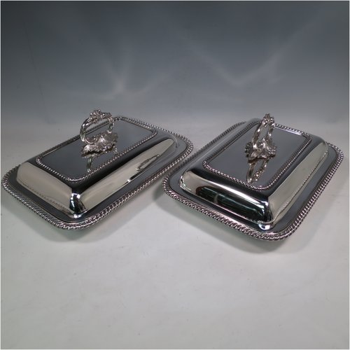 An Antique Georgian Old Sheffield plated pair of entrée dishes with covers, having rectangular bodies and rounded corners, with applied gadroon edge borders, and with removable bayonet-fit cast floral handles. All in original condition showing applied wires to edges and made in ca. 1815. The dimensions of this fine pair of hand-made Old Sheffield plated entrée dishes and covers are length 30 cms (11.75 inches), width 21.5 cms (8.5 inches).