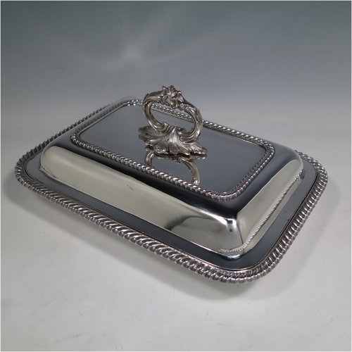 An Antique Georgian Old Sheffield plated pair of entrée dishes with covers, having rectangular bodies and rounded corners, with applied gadroon edge borders, and with removable bayonet-fit cast floral handles. All in original condition showing applied wires to edges and made in ca. 1815. The dimensions of this fine pair of hand-made Old Sheffield plated entrée dishes and covers are length 30 cms (11.75 inches), width 21.5 cms (8.5 inches).