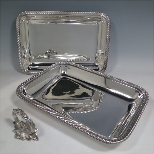 An Antique Georgian Old Sheffield plated pair of entrée dishes with covers, having rectangular bodies and rounded corners, with applied gadroon edge borders, and with removable bayonet-fit cast floral handles. All in original condition showing applied wires to edges and made in ca. 1815. The dimensions of this fine pair of hand-made Old Sheffield plated entrée dishes and covers are length 30 cms (11.75 inches), width 21.5 cms (8.5 inches).