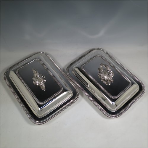 An Antique Georgian Old Sheffield plated pair of entrée dishes with covers, having rectangular bodies and rounded corners, with applied gadroon edge borders, and with removable bayonet-fit cast floral handles. All in original condition showing applied wires to edges and made in ca. 1815. The dimensions of this fine pair of hand-made Old Sheffield plated entrée dishes and covers are length 30 cms (11.75 inches), width 21.5 cms (8.5 inches).