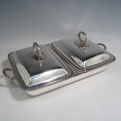 Sterling silver pair of entree dishes with covers and handles, sitting in an original plain rectangular hot-water warming frame, with applied gadroon borders and hand-pierced liners, having cast side-handles, and all sitting on four cushion feet. Made by D. & J. Wellby of London in 1916. The dimensions of this fine hand-made silver entree dish set are length 36 cms (14 inches), width 20 cms (8 inches), height including cover handles 12 cms (4.75 inches), and it weighs a total of approx. 1,965g (63 troy ounces).    