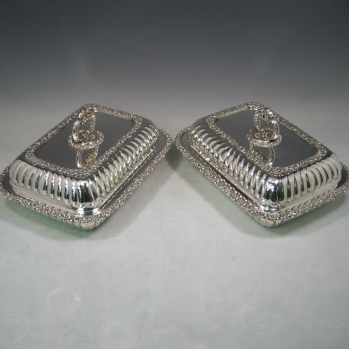 Antique Georgian Old Sheffield plated pair of entrée dishes with covers, having rectangular bodies and rounded corners, with hand-chased half-fluted decoration, applied cast floral bodies, and with removable bayonet-fit handles. All in original condition and made in ca. 1830. The dimensions of this fine pair of hand-made Old Sheffield plated entrée dishes and covers are length 28 cms (11 inches), width 23 cms (9 inches).