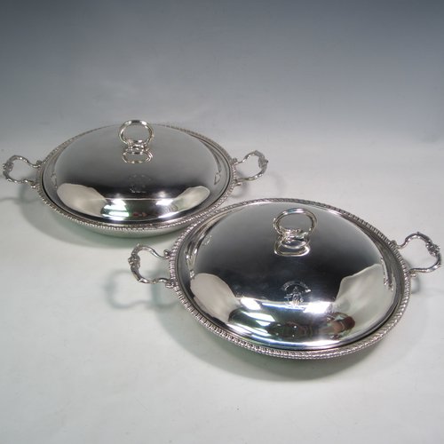 Antique Georgian sterling silver pair of entree or hash dishes with covers, having round bodies with applied gadroon borders and cast scroll side-handles, with plain domed lift-off covers having cast asparagus handles, an all sitting on flat bases. Made by Charles Wright of London in 1771. The dimensions of this pair of fine hand-made antique silver entree dishes and covers are diameter 24 cms (9.5 inches), height including cover handle 10 cms (4 inches), and they weigh a total of approx. 1,738g (56 troy ounces). Please note that both the bases and covers are crested.