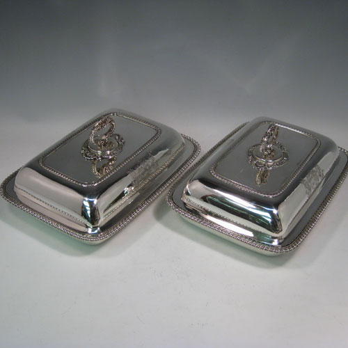 Antique Georgian pair of entree dishes with covers, having rectangular bodies with rounded corners, bayonet-fit removable gadroon and shell handles, gadroon borders, and sitting on flat bases. Made by Joseph Angell of London in 1817. The dimensions of this pair of fine hand-made antique silver entree dishes and covers are length 29 cms (11.5 inches), height including handle 13 cms (5 inches), width 21.5 cms (8.5 inches), and they weigh a total of approx. 3,120g (101 troy ounces). Please note that these are crested, and the Latin motto has been translated as The Moon Shall Fill Her Horns Again.