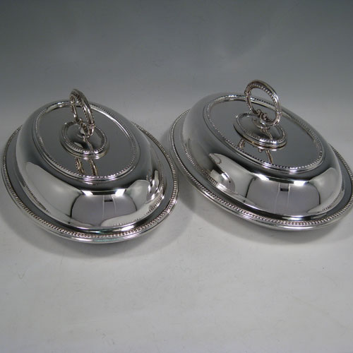    Sterling silver pair of entree dishes, having oval bodies, bead edges, and bayonet-fit removable loop handles. Made by Goldsmiths and Silversmiths of London in 1918. Length 25 cms (10 inches), width 18 cms (7 inches), height inc. handle 13 cms (5 inches). Total weight approx. 2,145g (69 troy ounces).