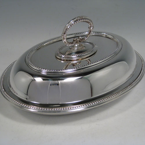    Sterling silver pair of entree dishes, having oval bodies, bead edges, and bayonet-fit removable loop handles. Made by Goldsmiths and Silversmiths of London in 1918. Length 25 cms (10 inches), width 18 cms (7 inches), height inc. handle 13 cms (5 inches). Total weight approx. 2,145g (69 troy ounces).