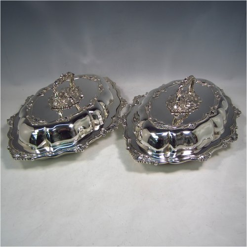 A very handsome Antique Sterling Silver pair of entree dishes, having oval lobed bodies, with lift-off lids, removable bayonet-fit handles, applied cast floral and scroll borders, and sitting on flat bases. These elegant silver entree dishes and covers were made by James Dixon & Sons of Sheffield in 1918. The dimensions of this fine pair of hand-made antique silver entree dishes and covers are length 35 cms (13.75 inches), width 26 cms (10.25 inches), and they weigh a total of approx. 3,472g (112 troy ounces).  