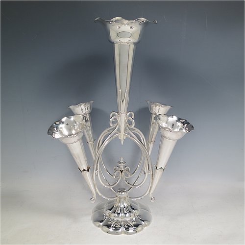 An Antique Victorian Silver Plated Art Nouveau flower vase epergne center-piece, having five removable flower vases, with a central larger vase, all sitting on a base with wire-work scrolls and melon-style fluting. All made in ca. 1890. The dimensions of this fine hand-made silver-plated flower epergne are height 37 cms (14.5 inches), and spread across vases 28 cms (11 inches).  