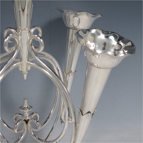 An Antique Victorian Silver Plated Art Nouveau flower vase epergne center-piece, having five removable flower vases, with a central larger vase, all sitting on a base with wire-work scrolls and melon-style fluting. All made in ca. 1890. The dimensions of this fine hand-made silver-plated flower epergne are height 37 cms (14.5 inches), and spread across vases 28 cms (11 inches).  