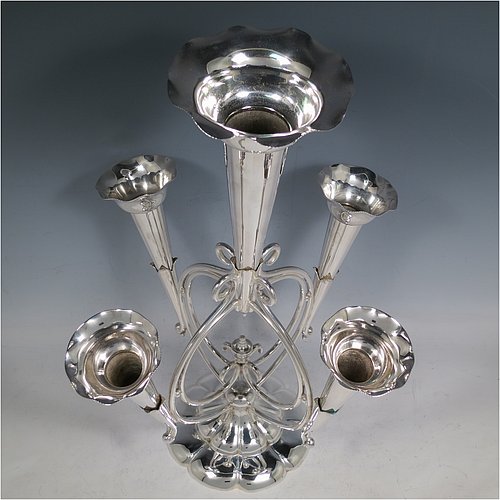 An Antique Victorian Silver Plated Art Nouveau flower vase epergne center-piece, having five removable flower vases, with a central larger vase, all sitting on a base with wire-work scrolls and melon-style fluting. All made in ca. 1890. The dimensions of this fine hand-made silver-plated flower epergne are height 37 cms (14.5 inches), and spread across vases 28 cms (11 inches).  