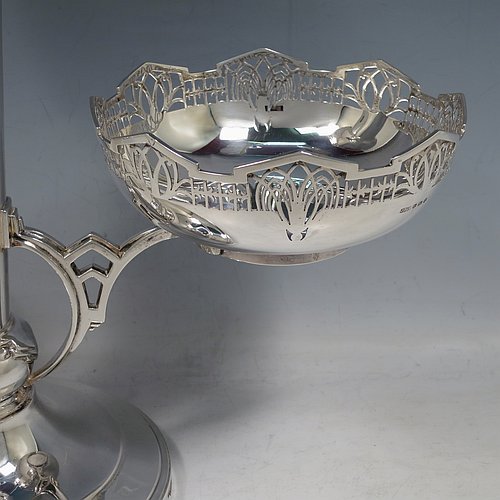 An Art Deco Sterling Silver table centrepiece or epergne, with hand-pierced geometrical style borders and Art Deco motifs, having one central flower vase, and two removable dishes resting on side arms, and all sitting on a pedestal base with four flanged feet. Made by James Dixon & Sons of Sheffield in 1934. The dimensions of this fine hand-made Art Deco style epergne or center-piece are height 33 cms (13 inches), width across arms 41 cms (16 inches), depth 16 cms (6.3 inches), and with a total weight of approx. 1,309 (42 troy ounces).   