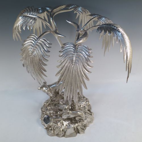 A very handsome Antique Victorian silver-plated table palm tree center-piece, having two palm trees inter-twined with a total of seven fronds, standing underneath which are two cast models of playful greyhounds or lurchers, and all sitting on a round naturalistic cast rock base. Made by Elkington and Co. with a date letter mark for 1852. The dimensions of this fine hand-made silver-plated table centerpiece display are height 41 cms (16 inches), spread across fronds 31 cms (12.25 inches), and diameter at base 20 cms (8 inches).

  